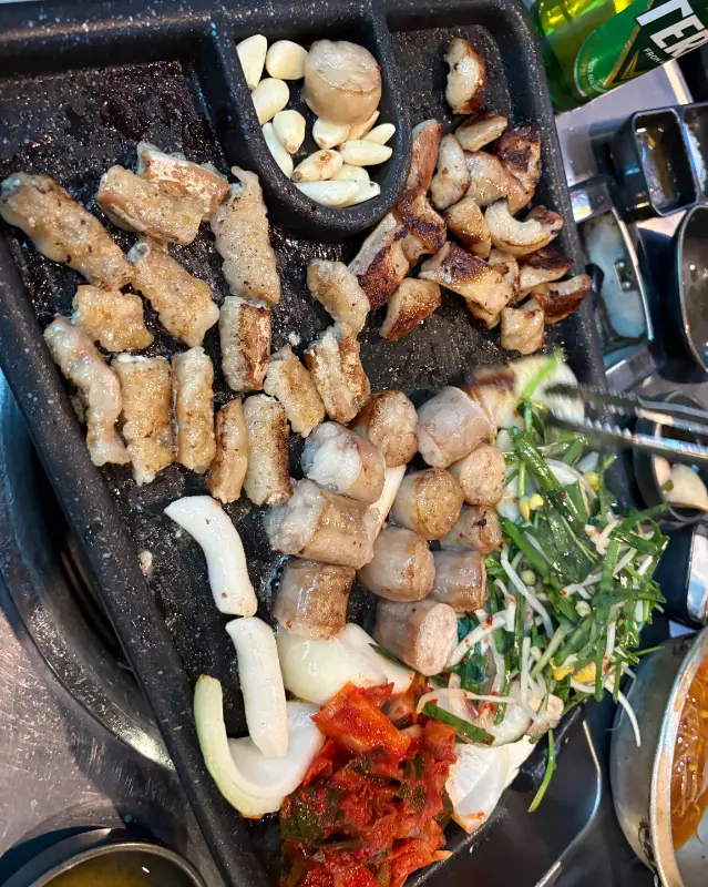 불판 위에 올려진 곱창, 김치, 양파의 조화
