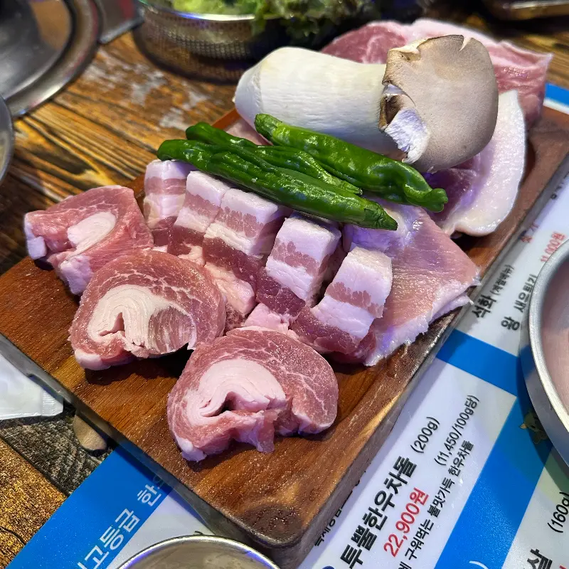 두툼한 고기와 버섯, 꽈리꼬추가 담긴 나무 도마