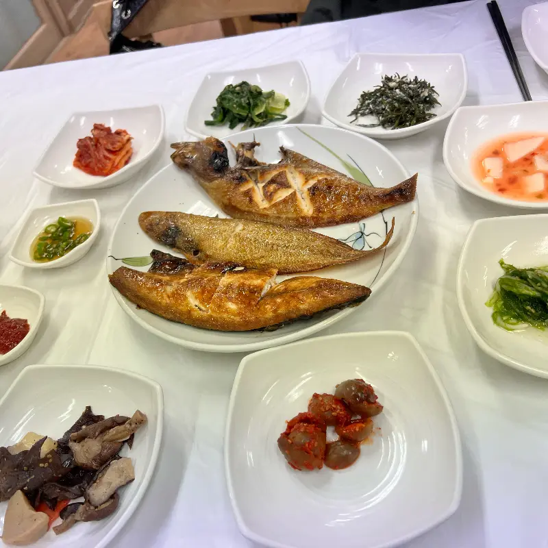 다양한 밑반찬과 생선구이가 함께 놓여 있는 모습