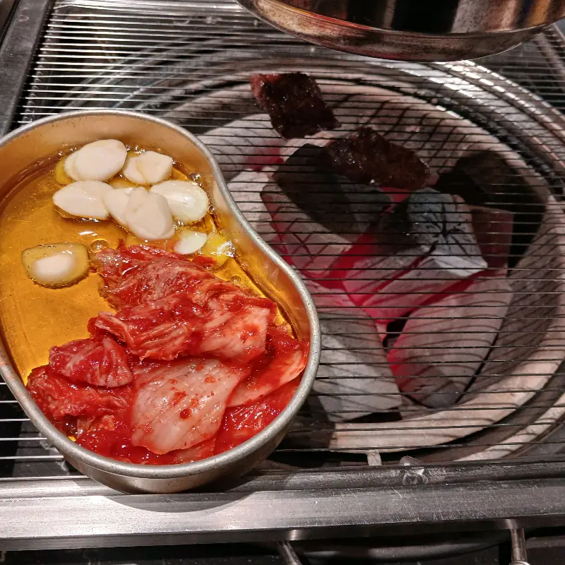 불판 위에서 구워지는 김치와 마늘