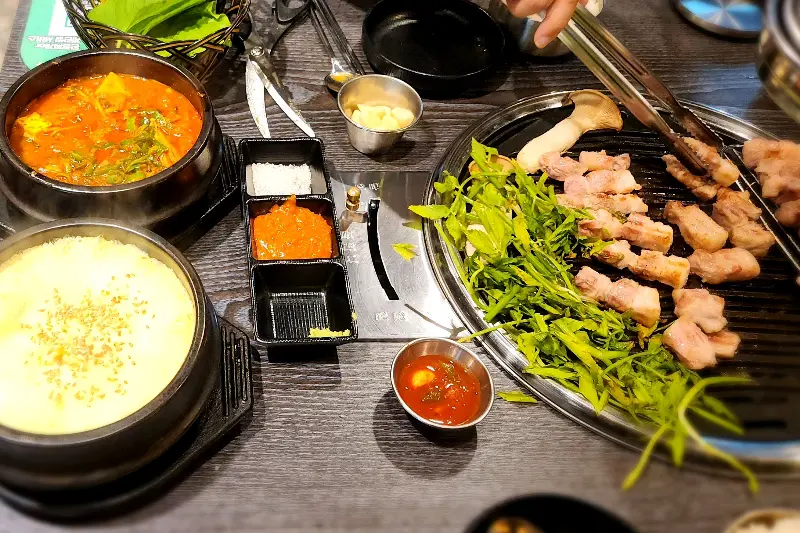 한 상 가득 차려진 삼겹살과 밑반찬, 찌개의 모습