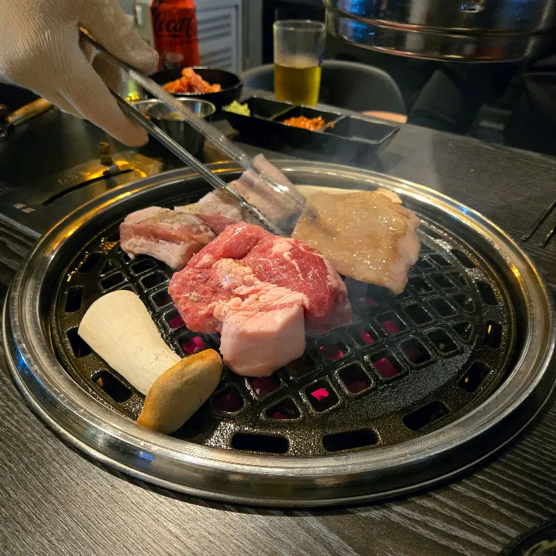 숯불 위에서 구워지고 있는 두툼한 삼겹살의 모습