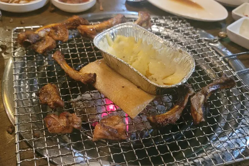 숯불 위에서 치즈와 함께 구워지는 쪽갈비와 돼지껍데기