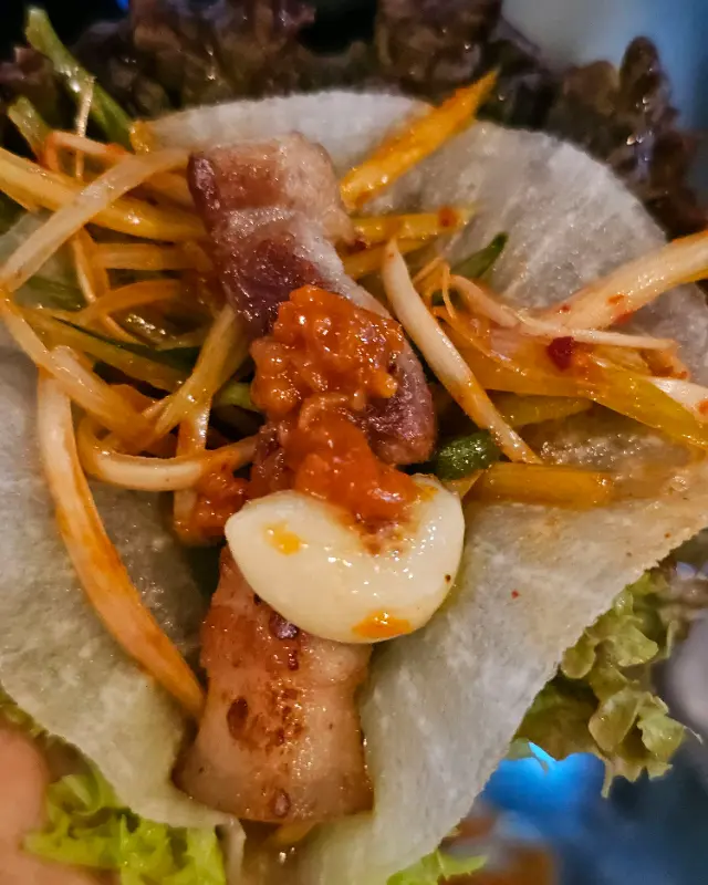 쌈 채소에 막창, 파김치, 마늘을 올려 먹는 모습