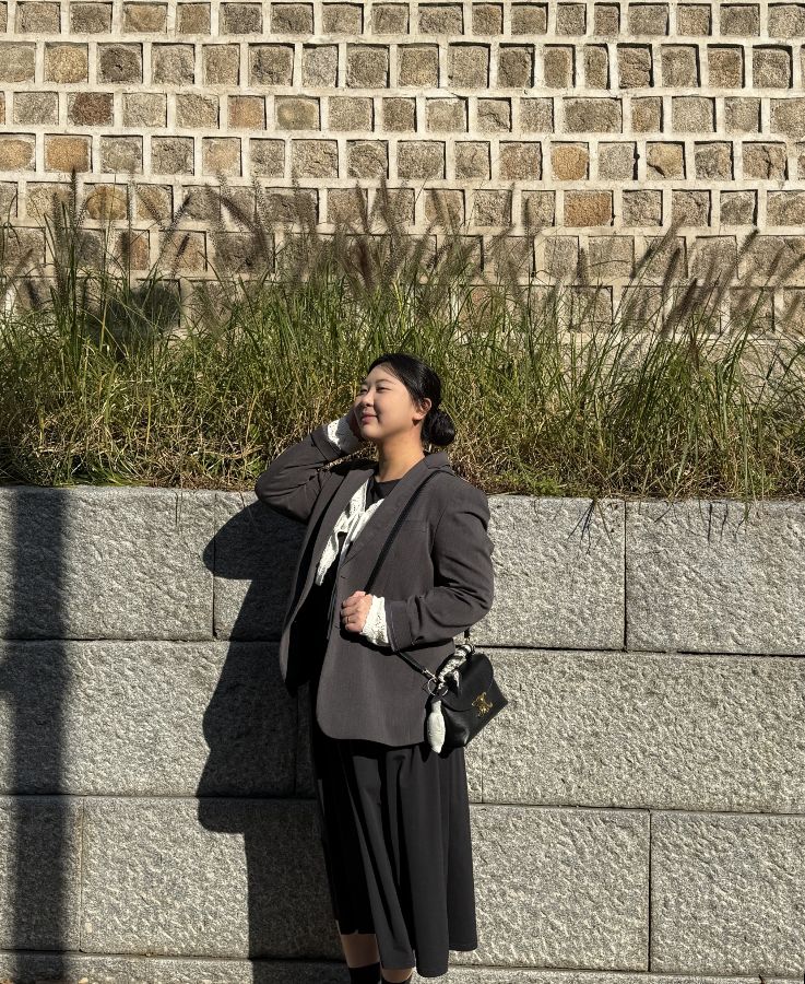 담벼락 앞에서 사진을 찍는 여성