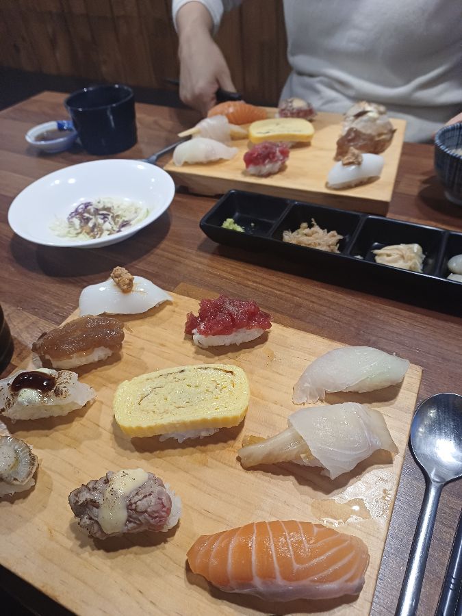 테이블 위에 놓인 두 개의 초밥 접시와 다양한 곁들임