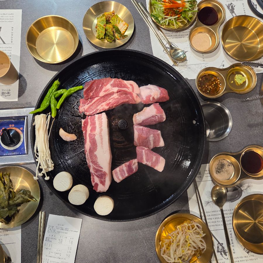 맛있게 구워진 삼겹살을 쌈에 싸서 먹는 모습