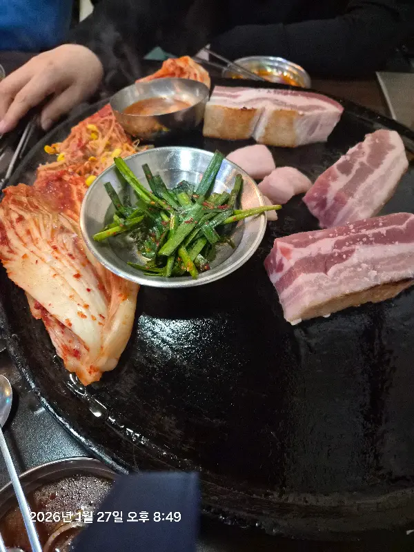 잘 익은 삼겹살 한 점을 젓가락으로 집어 올리는 모습