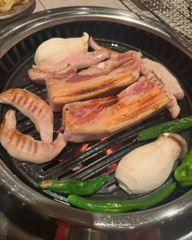 불판 위에서 구워지는 오겹살, 버섯, 꽈리고추