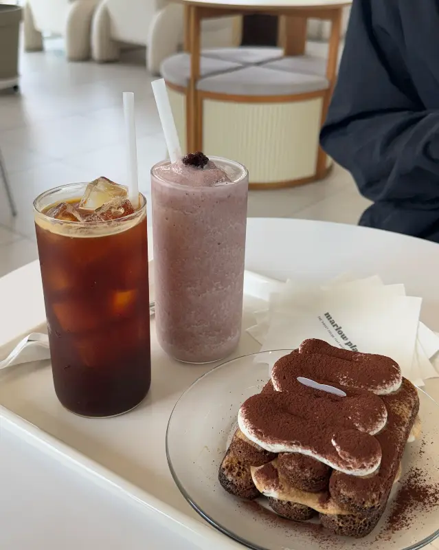 음료 두 잔과 티라미슈 케이크 한 조각이 테이블 위에 놓여있다.