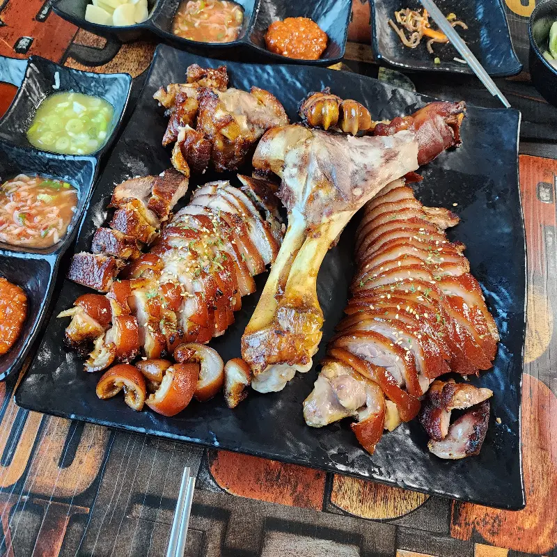 다양한 소스와 곁들임 채소가 함께 제공되는 족발 한 상