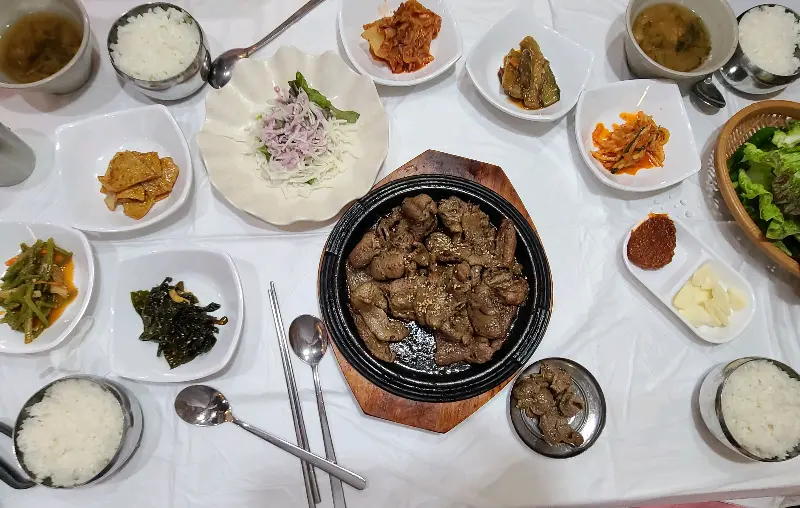 숯불고기를 중심으로 다양한 반찬들이 놓여있는 테이블 전경