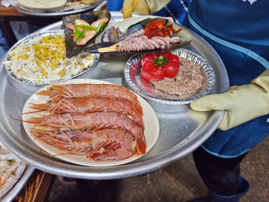 다양한 해산물과 곁들임 메뉴가 담긴 쟁반을 직원이 들고 있는 모습