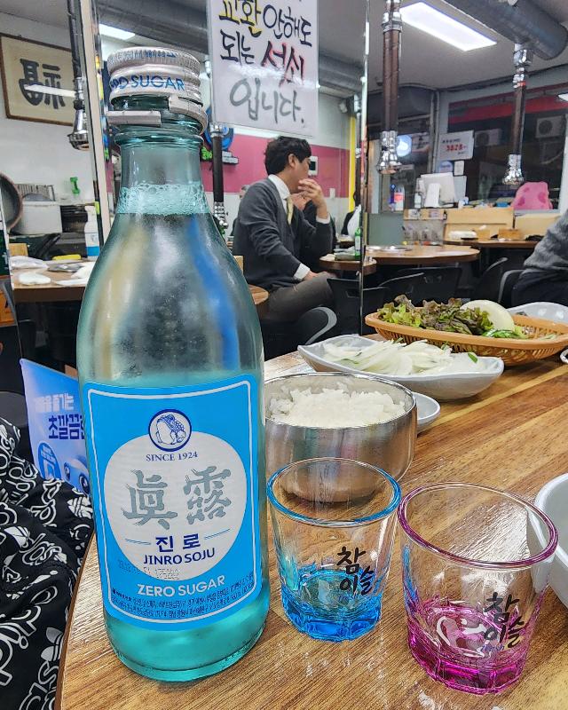 진로 소주 병과 함께 놓인 파란색과 분홍색의 예쁜 술잔들