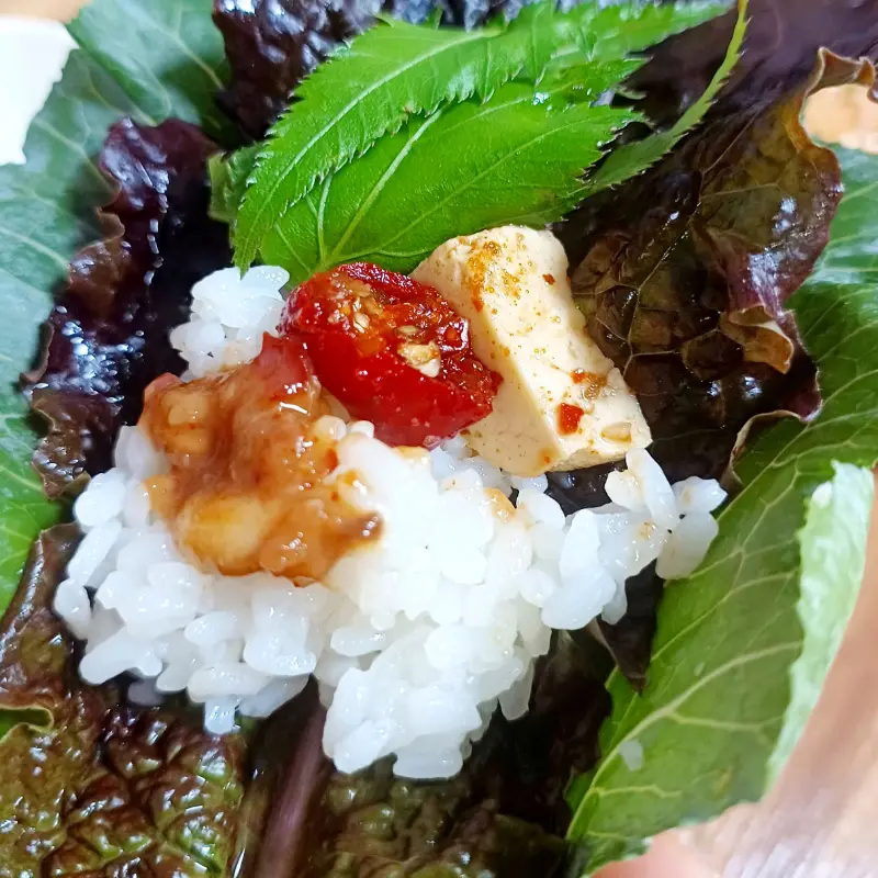 쌈 채소에 밥과 나물을 올려 한 입 가득