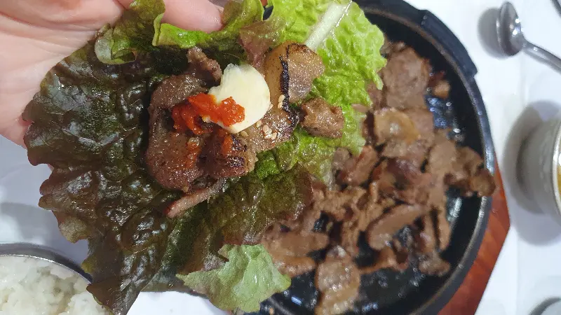 상추에 숯불고기와 쌈장, 마늘을 올려 쌈을 싸 먹는 모습