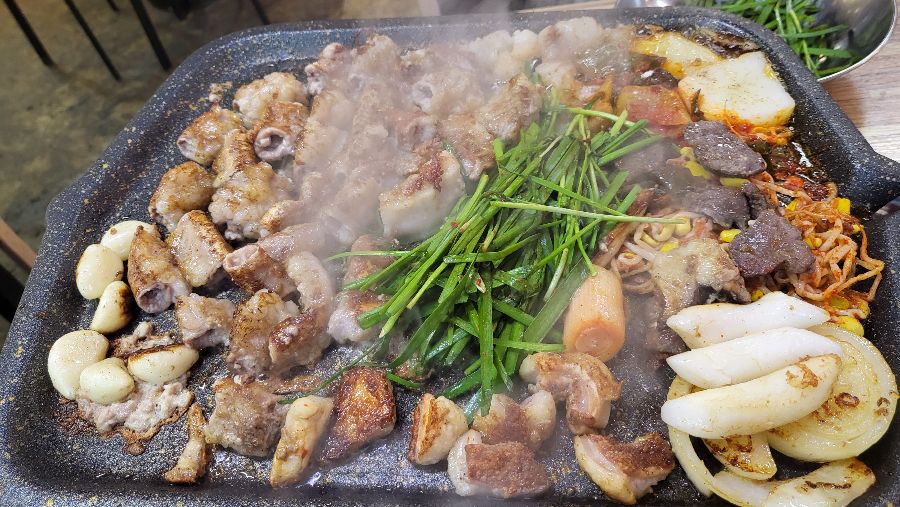 불판 위에서 익어가는 곱창, 막창, 염통, 떡, 마늘, 부추