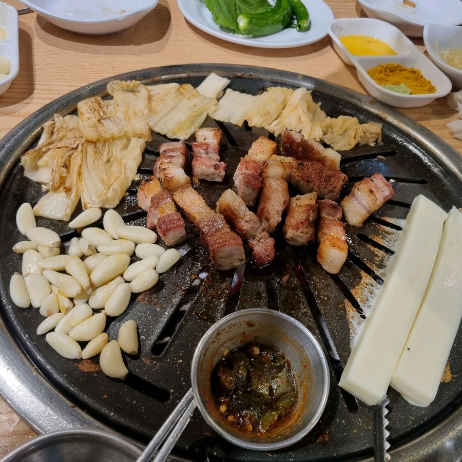 노릇하게 구워진 삼겹살과 다양한 곁들임