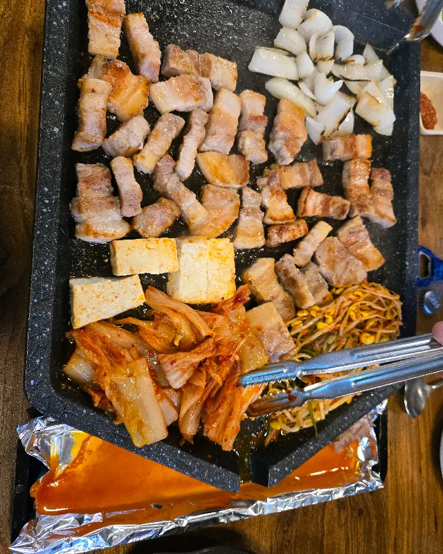 불판 위에서 익어가는 삼겹살과 김치