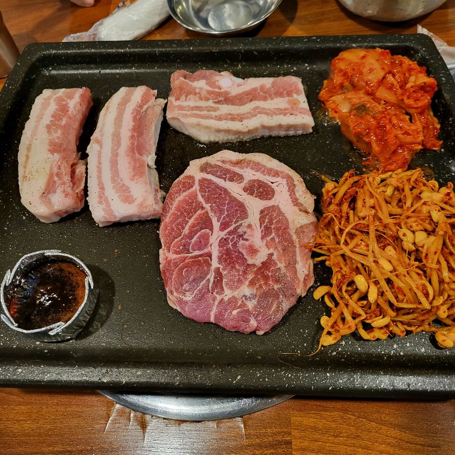 불판 위 삼겹살과 목살, 김치, 콩나물의 조화