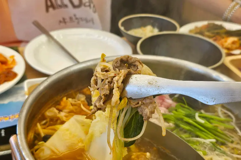 샤브샤브 냄비에서 집게로 고기를 건져 올리는 모습