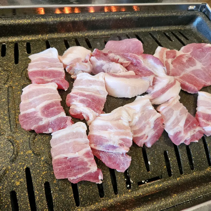 불판 위에 올려진 생삼겹살의 모습