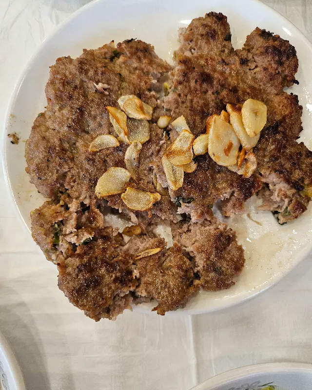 두툼한 떡갈비 위에 올려진 마늘칩