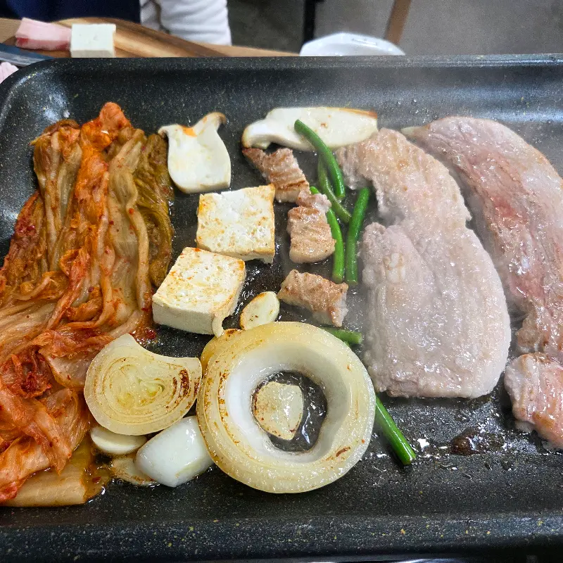 불판 위에서 익어가는 삼겹살과 묵은지