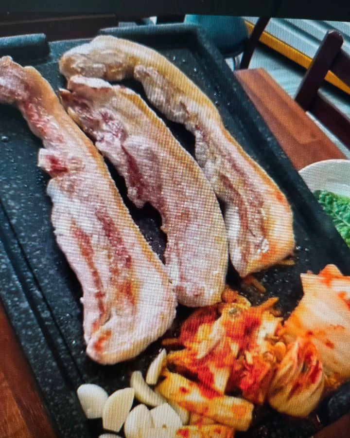 불판 위의 삼겹살과 김치, 마늘