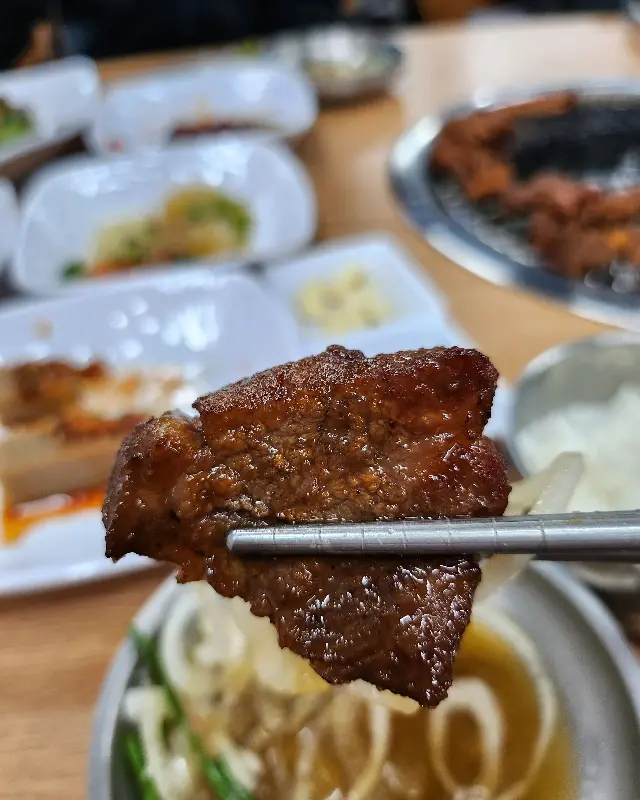 젓가락으로 집어 올린 돼지갈비 한 점