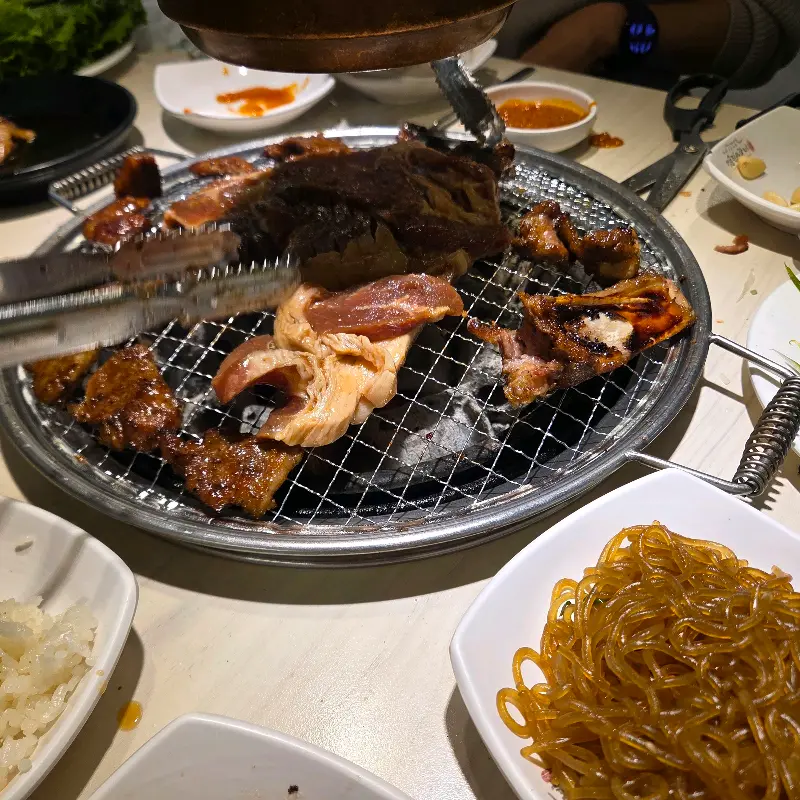 불판 위에 구워진 갈비와 곁들임 메뉴