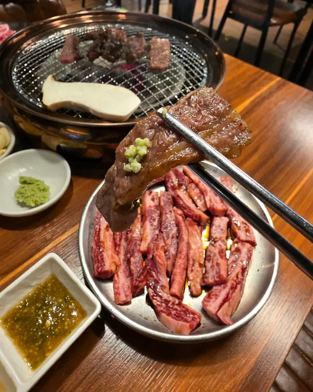 잘 구워진 갈비살을 젓가락으로 집어 올리는 모습