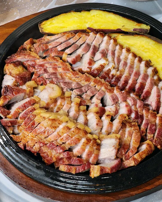 노릇하게 구워진 훈제 삼겹살과 구운 고구마가 철판 위에 가지런히 놓여 있는 사진