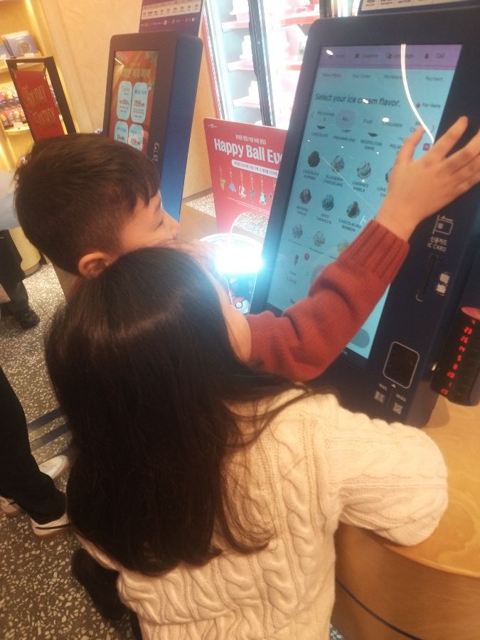키오스크에서 메뉴를 고르는 아이들