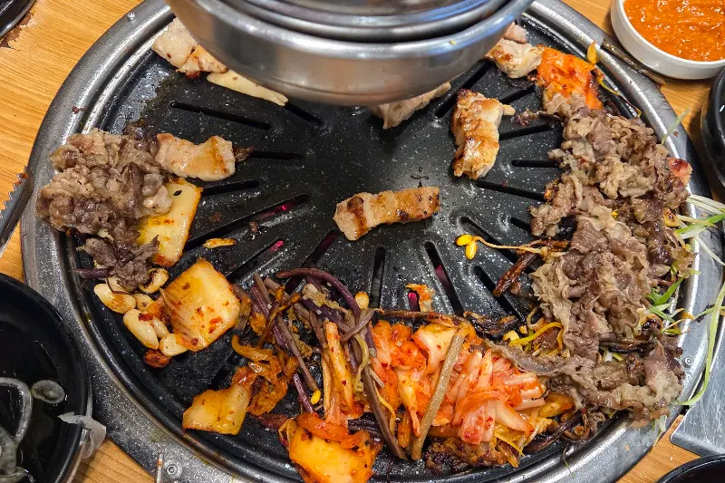 불판 위에서 맛있게 익어가는 삼겹살과 김치, 우삼겹