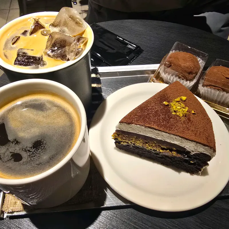 쑥 갸또 케이크와 커피가 함께 놓여있는 모습. 케이크 위에 뿌려진 콩가루가 인상적이다.