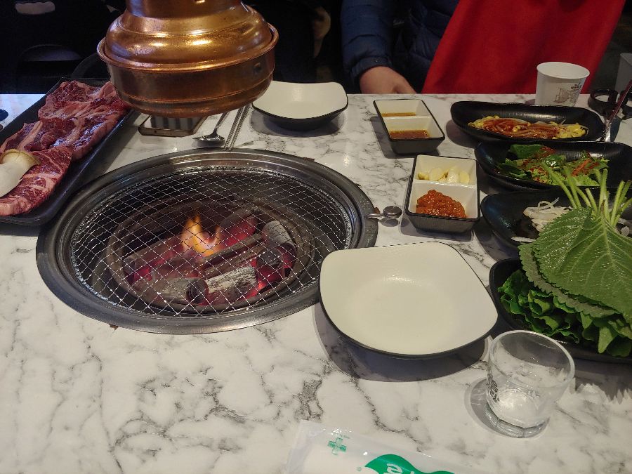 화로 옆에 가지런히 놓인 다양한 곁들임과 쌈채소