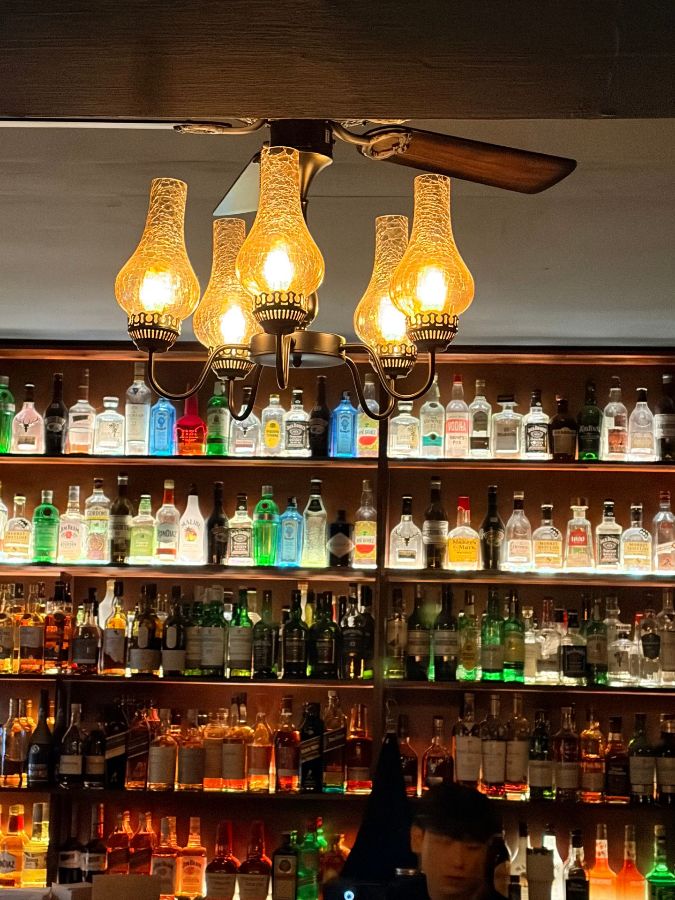 천장에 매달린 앤티크한 조명이 술병들을 은은하게 비추고 있다.