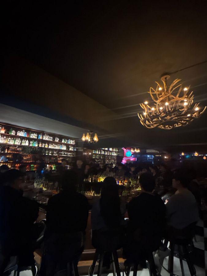 어두운 조명 아래, 삼삼오오 모여앉아 술을 즐기는 손님들의 모습