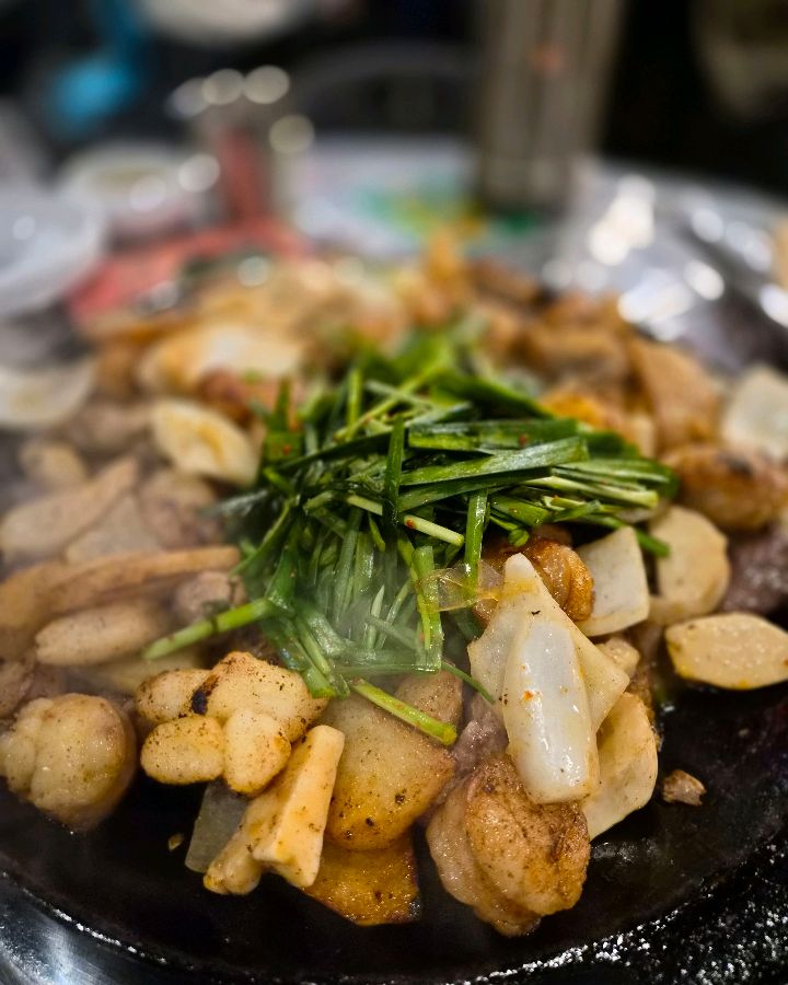 잘 구워진 곱창 위에 부추가 얹어져 있는 모습