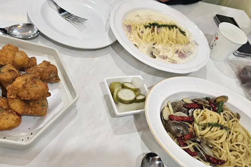 봉골레 파스타와 튀김, 피클이 놓인 테이블