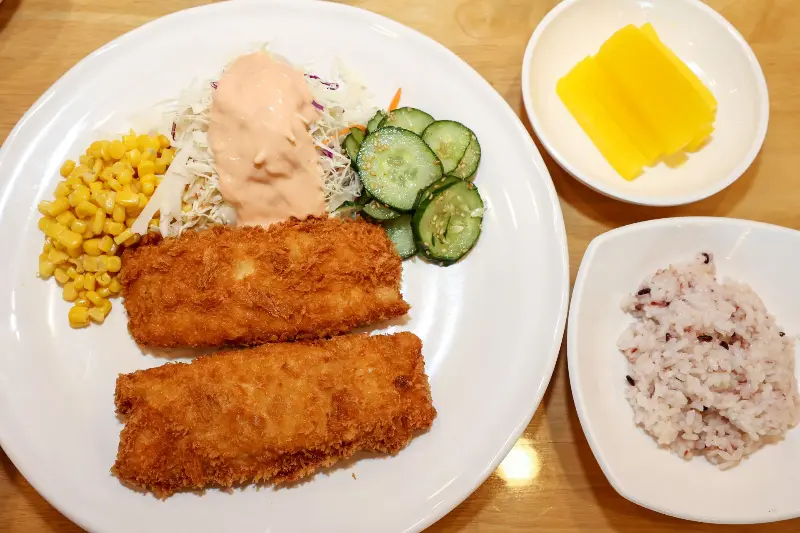 접시에 담긴 돈까스와 샐러드, 밥, 그리고 단무지의 모습