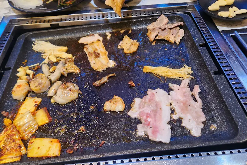 불판 위에서 익어가는 다양한 종류의 고기