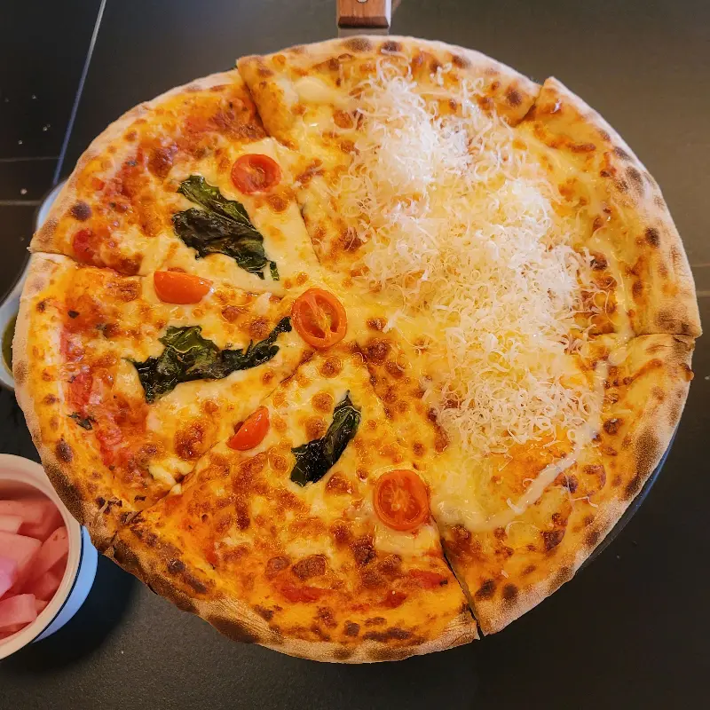 마르게리따 피자와 또 다른 맛의 피자가 반반씩 담겨있는 피자
