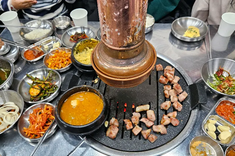 고기와 다양한 반찬들이 함께 놓여 있는 테이블 전경