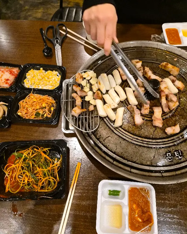 숯불 위에서 삼겹살과 떡이 구워지는 모습