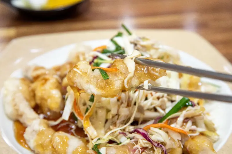 탕수육 한 조각을 젓가락으로 집어 올리는 모습