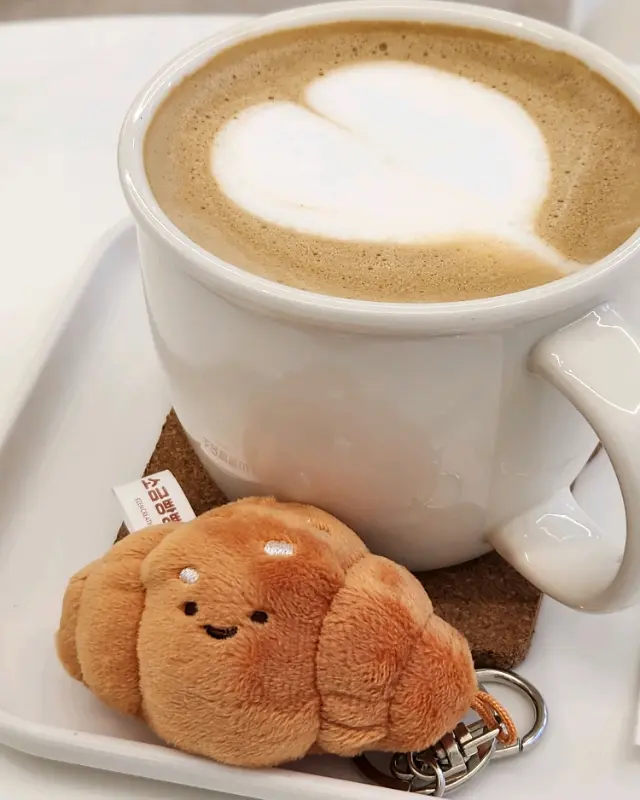 귀여운 크루아상 키링과 함께 제공되는 라떼