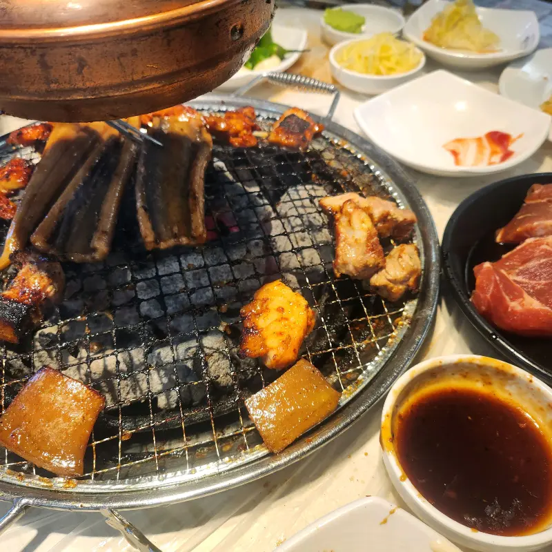 불판 위에 돼지갈비, 장어, 돼지 껍데기 등이 함께 구워지고 있는 모습