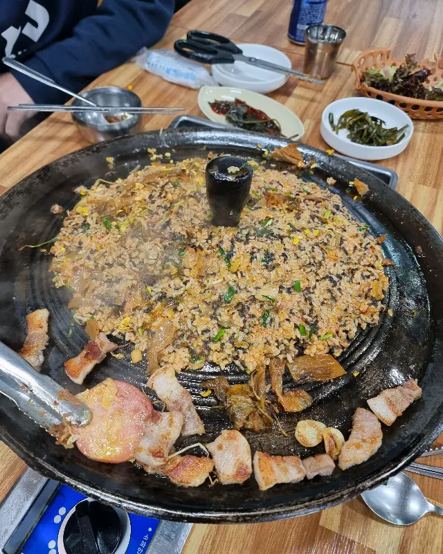 솥뚜껑 위에 볶음밥이 넓게 펼쳐져 있는 모습